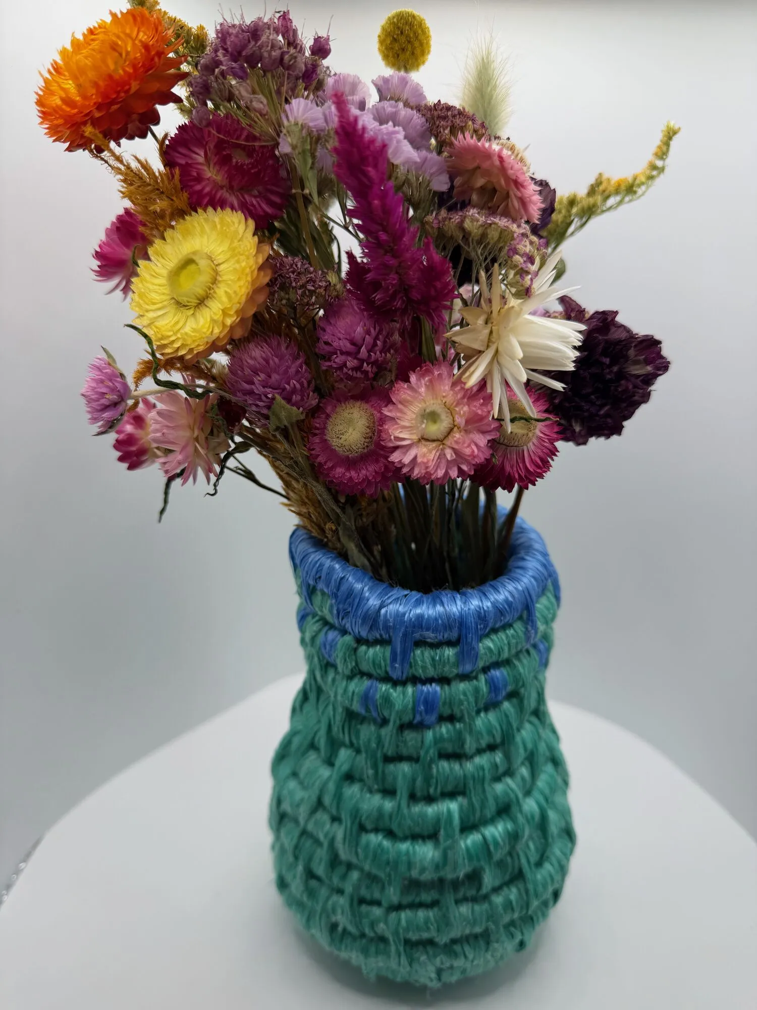 Aqua rope vase with a blue rim and dried flowers